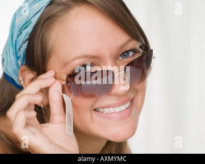 Young woman smiling et essayer sur des lunettes Banque D'Images