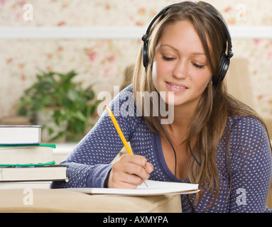 Jeune femme portant des écouteurs et à faire leurs devoirs Banque D'Images