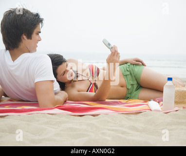 Couple avec cell phone on blanket at beach Banque D'Images