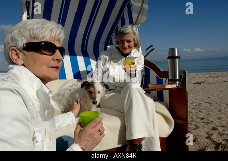 Deux femmes d'âge mûr assis dans des chaises à la plage de la mer Baltique et un pique-nique Banque D'Images