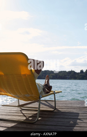 L'homme sur une chaise de plage au bord du lac partie de Banque D'Images