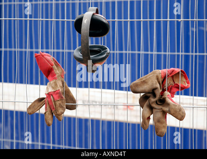 Paire de gants de protection et Eardprotectors constructeurs accroché sur une clôture à plateau de pause. Banque D'Images