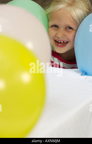 Petite fille blonde coller la tête par un groupe de ballons, close-up Banque D'Images