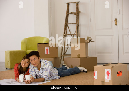 Couple asiatique sur le plancher à côté de boîtes de déménagement Banque D'Images