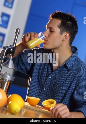 Jeune homme de boire le jus d'orange à la maison. Banque D'Images