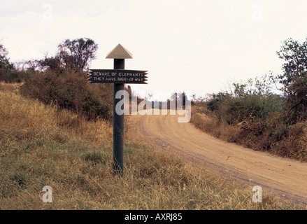 Road sign reading MÉFIEZ-VOUS DES ÉLÉPHANTS QU'ILS ONT DROIT DE PASSAGE dans le parc national de Tsavo Ouest Kenya Afrique de l'Est Banque D'Images