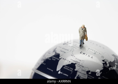 Businessman with briefcase figurine walking on globe Banque D'Images