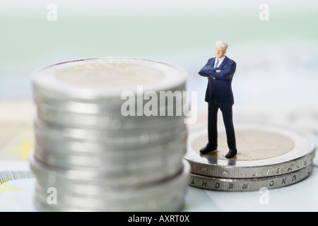 Figurine homme debout sur une pile de pièces Banque D'Images