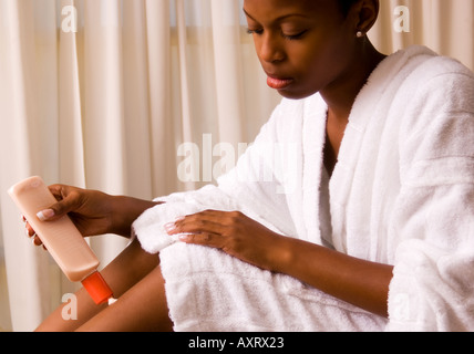 Jolie femme jamaïcaine 18 à 20 s'applique une lotion pour le corps à Leg USA Banque D'Images