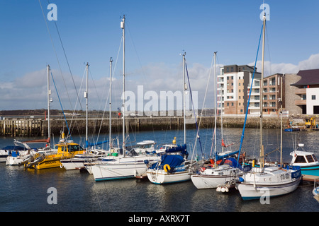Bateaux amarrés dans la marina à Victoria Dock avec nouveau développement au bord de l'eau à Caernarfon Gwynedd North Wales UK Banque D'Images