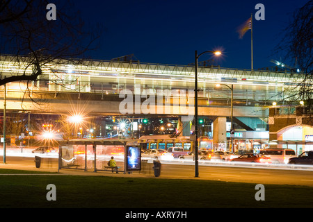 Bien que le trafic se déplace par, le dirigeant d'une personne attend un bus dans la rue principale de la station de SkyTrain Vancouver BC Canada Banque D'Images