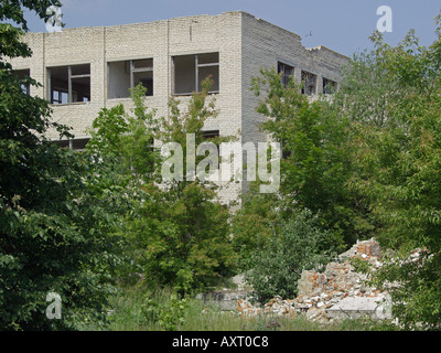 Zone d'exclusion de Tchernobyl abandonnée en décomposition à l'abandon trois étages de briques rouges au milieu prospère riche feuillage, Bélarus Banque D'Images