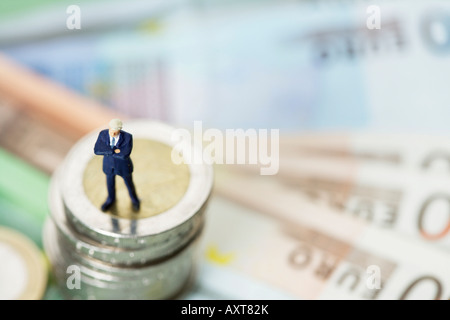 Figurine homme debout sur une pile de pièces Banque D'Images