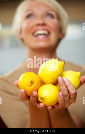 Mature Woman holding d'un groupe moyen de citrons dans ses mains, close-up Banque D'Images