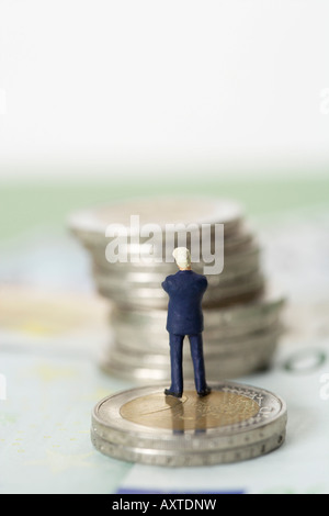 Figurine homme debout sur une pile de pièces Banque D'Images