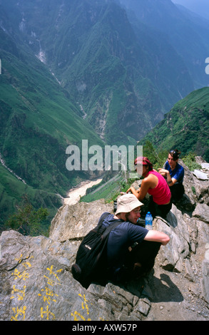 Voyageurs de prendre une pause tout en haut trekking au-dessus de la rivière Yangtze dans la Gorge du tigre bondissant dans la province du Yunnan. Banque D'Images