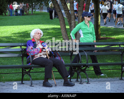 Female jogger et femme âgée de détente à un banc de parc, USA, Manhattan, New York Banque D'Images