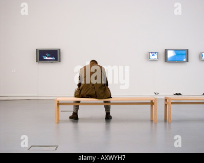 Un homme assis par lui-même à une exposition de l'artiste gallois Tim Davies à Aberystwyth Arts Centre Ceredigion Pays de Galles UK Banque D'Images