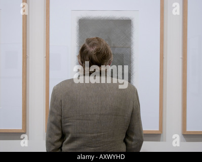 Un homme à la recherche de travail d'art encadrée par l'artiste gallois Tim Davies dans une exposition Aberystwyth Arts Centre Ceredigion Pays de Galles UK Banque D'Images
