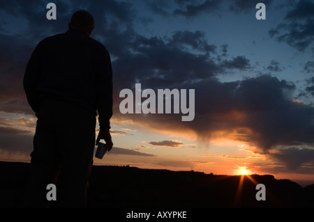 L'homme en silhouette avec tasse de café en regardant le lever du soleil sur le Big Horn Mountains Wyoming USA après une longue montée Banque D'Images