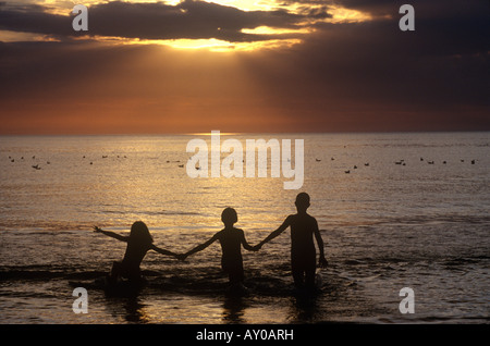 Personnes enfants silhouette sur la plage pendant le coucher du soleil lever du soleil Banque D'Images