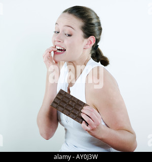 Studio portrait sur fond isolé d'une belle jeune femme de race blanche tenant une tablette de chocolat Banque D'Images