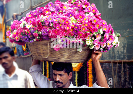 Un porteur transportant un panier de canne avec une charge odorante à Dadar Marché aux fleurs le plus grand marché aux fleurs en gros à Mumbai. L'Inde Banque D'Images