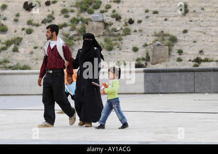 Un couple, dont un homme et son épouse vêtue de la burqa et de leurs enfants se rendant sur le citidel d'Alep, en Syrie. Banque D'Images