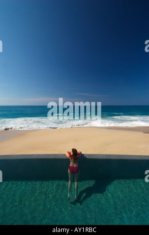 Femme en piscine à débordement donnant sur l'océan Banque D'Images