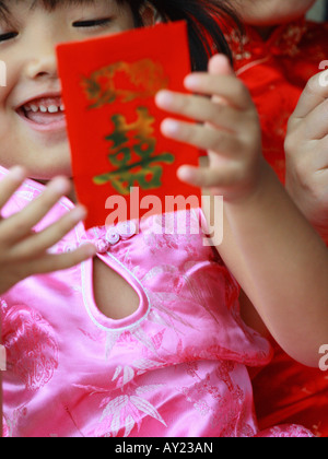 Close-up of a Girl holding un paquet cadeau rouge (Hong Bao) avec sa mère Banque D'Images