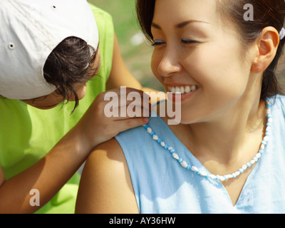 Close-up of a Boy putting un collier autour du cou de sa mère Banque D'Images