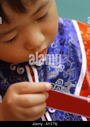 Close-up of a Boy de l'ouverture d'un paquet cadeau rouge (Hong Bao) Banque D'Images