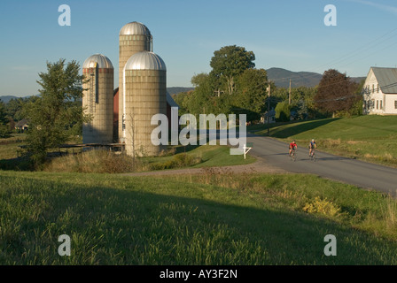 Deux hommes le vélo de route en montée sur un après-midi de la fin de l'été passé, une grange avec trois silos à Waitsfield Vermont Banque D'Images