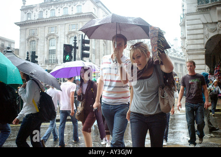 Les gens de marcher sous les parasols pendant une forte pluie douche dans le centre de Londres Banque D'Images