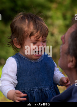 Grand-père réconfortant petite fille de 15 mois Banque D'Images