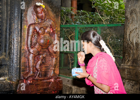 Jeune femme debout à côté de culte représentant la déesse de la fertilité, Temple Meenakshi, Madurai, Tamil Nadu, Inde Banque D'Images