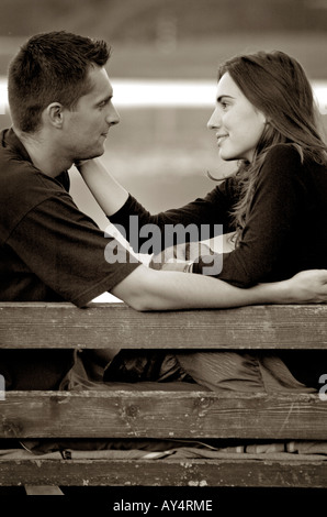 Young couple sitting on bench embrassant vue côté face à face Banque D'Images