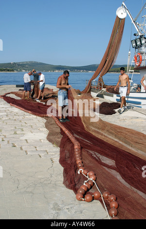 Les pêcheurs réparant les filets de pêche sur un quai en Croatie Europe Banque D'Images