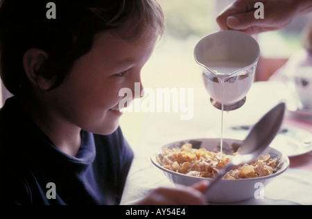 Jeune garçon ayant le petit déjeuner de céréales et lait frais Banque D'Images