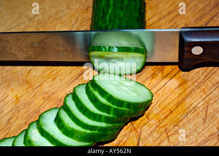 Tranches de concombre anglais avec des couteaux de cuisine sur une planche à découper en bois Banque D'Images