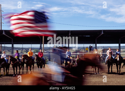 Un cow-boy au grand galop les mouches fièrement le drapeau de l'hymne national, à l'assemblée annuelle 4-H Rodeo tenue à Capitan, Nouveau Mexique. Banque D'Images