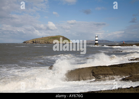 Penmon Point Ile d'Anglesey au nord du Pays de Galles UK Mars Les vagues se briser sur la plage et la colonne du phare protège voyage Banque D'Images