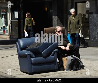 Déplacées à l'homme est assis dans un fauteuil inclinable sur les trottoirs de la ville Banque D'Images