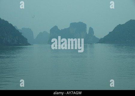 La baie d'Halong est habituellement photographiés en plein soleil avec ciel bleu. Cette image a été prise lorsque la nuit avait rempli la baie avec une étrange lumière bleue. Banque D'Images