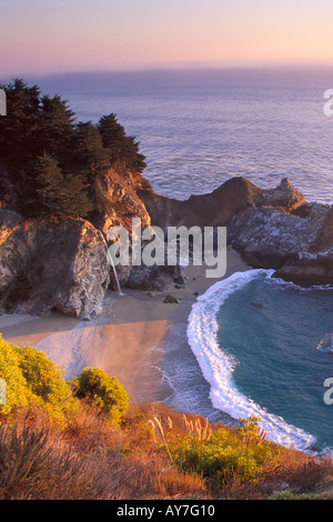 Cascade le long de la côte du Pacifique de Big Sur au coucher du soleil sur une journée calme avec des vagues sur une paisible plage de sable Banque D'Images