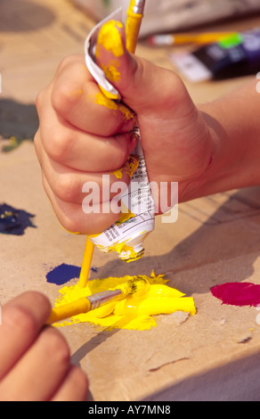 La main de l'enfant serrant un tube de peinture jaune, à la Fine Art Jours de Lincoln, Nouveau Mexique. Banque D'Images