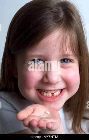 Litlle girl holding sa dent manquante Banque D'Images