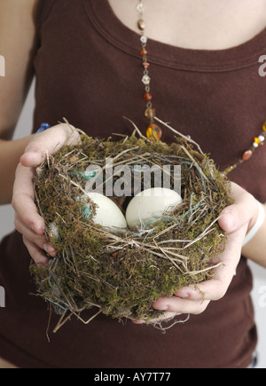 Un nid avec des oeufs étant tenu par une jeune femme portant des perles Banque D'Images