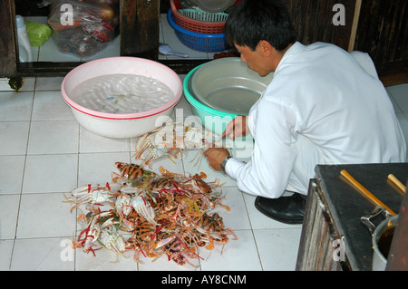 Un cuisinier préparant des fruits de mer sur un bateau de croisière, baie d'Halong, Vietnam Banque D'Images