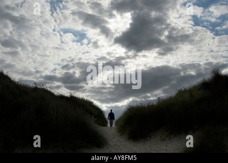 Figure marche à travers les dunes de sable contre moody sky UK Norfolk Banque D'Images